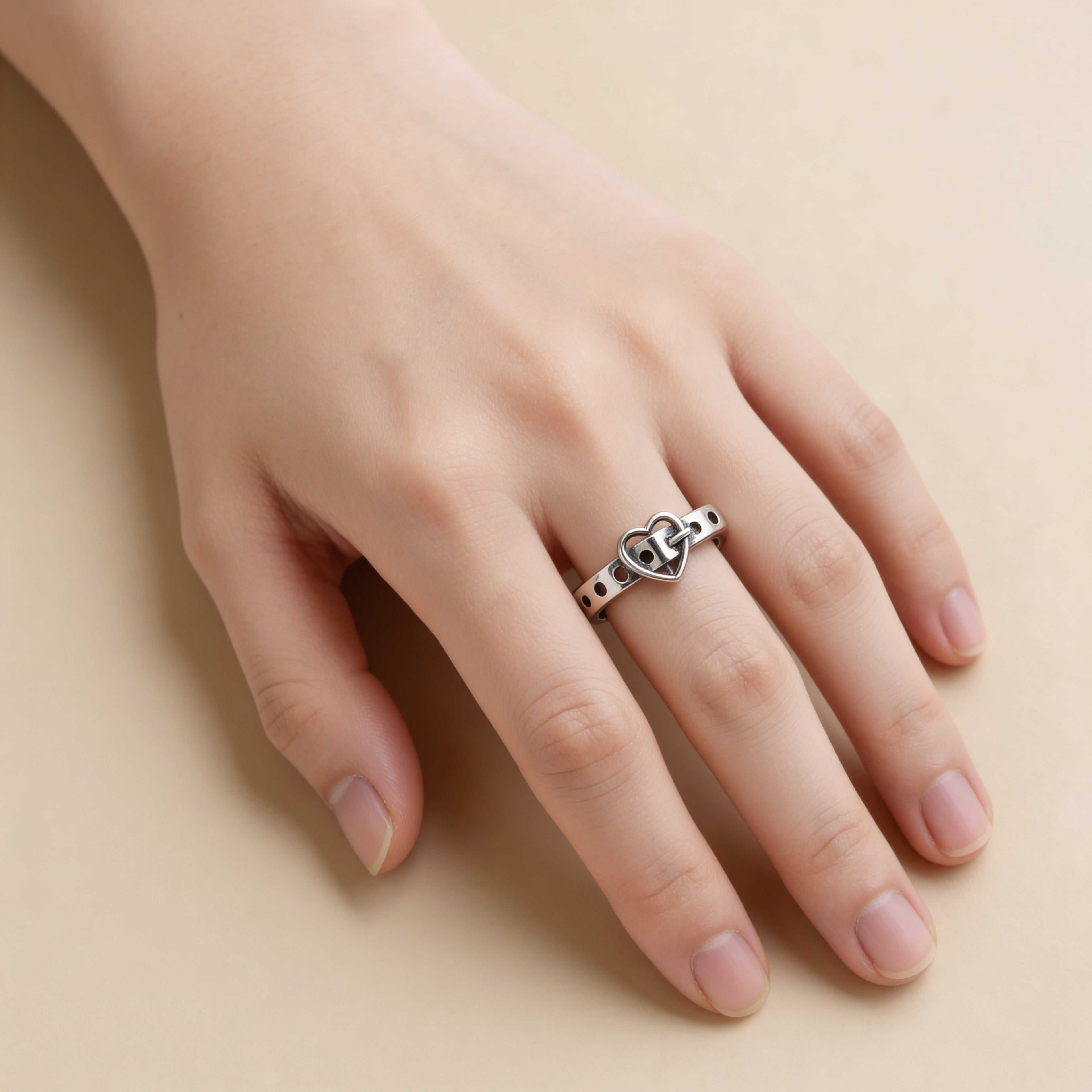 Minimalist silver heart buckle ring styled on hand, adjustable love-inspired jewelry.