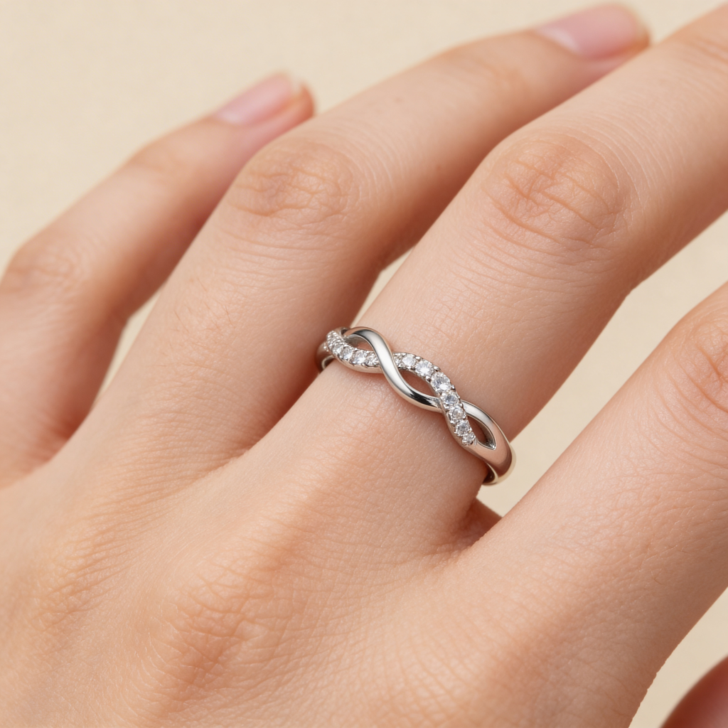 Adjustable silver infinity promise ring worn on hand, dainty twisted band design.