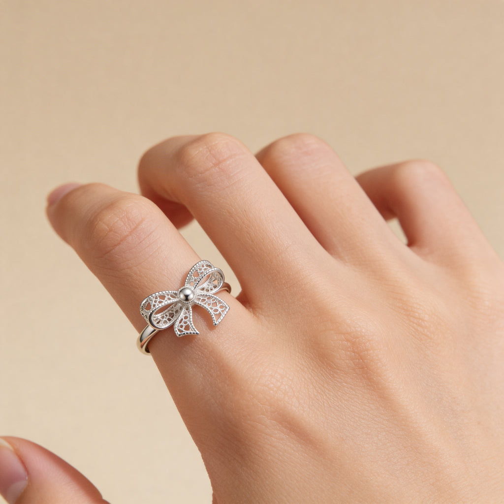 Adjustable silver bow statement ring worn on hand, feminine fashion jewelry for women.