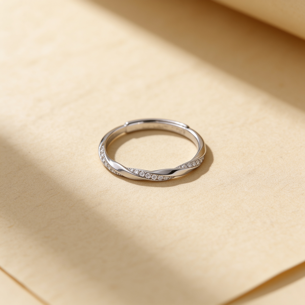 Adjustable silver plated twist ring with sparkling crystal accents displayed on a warm beige background