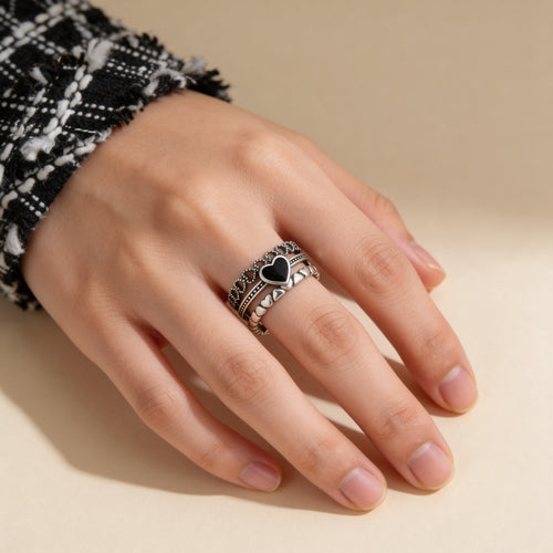 Silver adjustable ring with black heart centre worn on finger with layered band detail