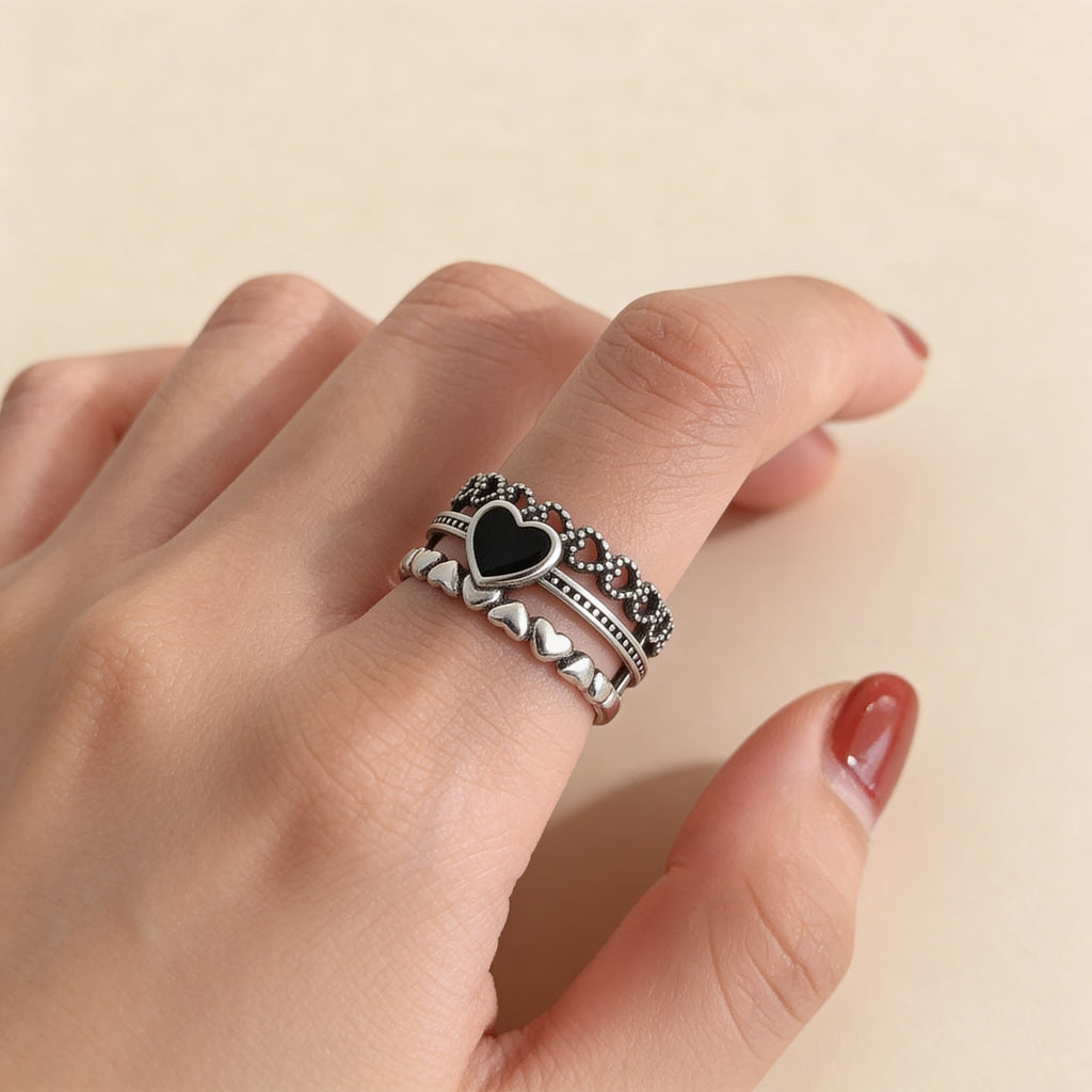 Black heart silver ring worn on hand with stacked layered design and textured detailing
