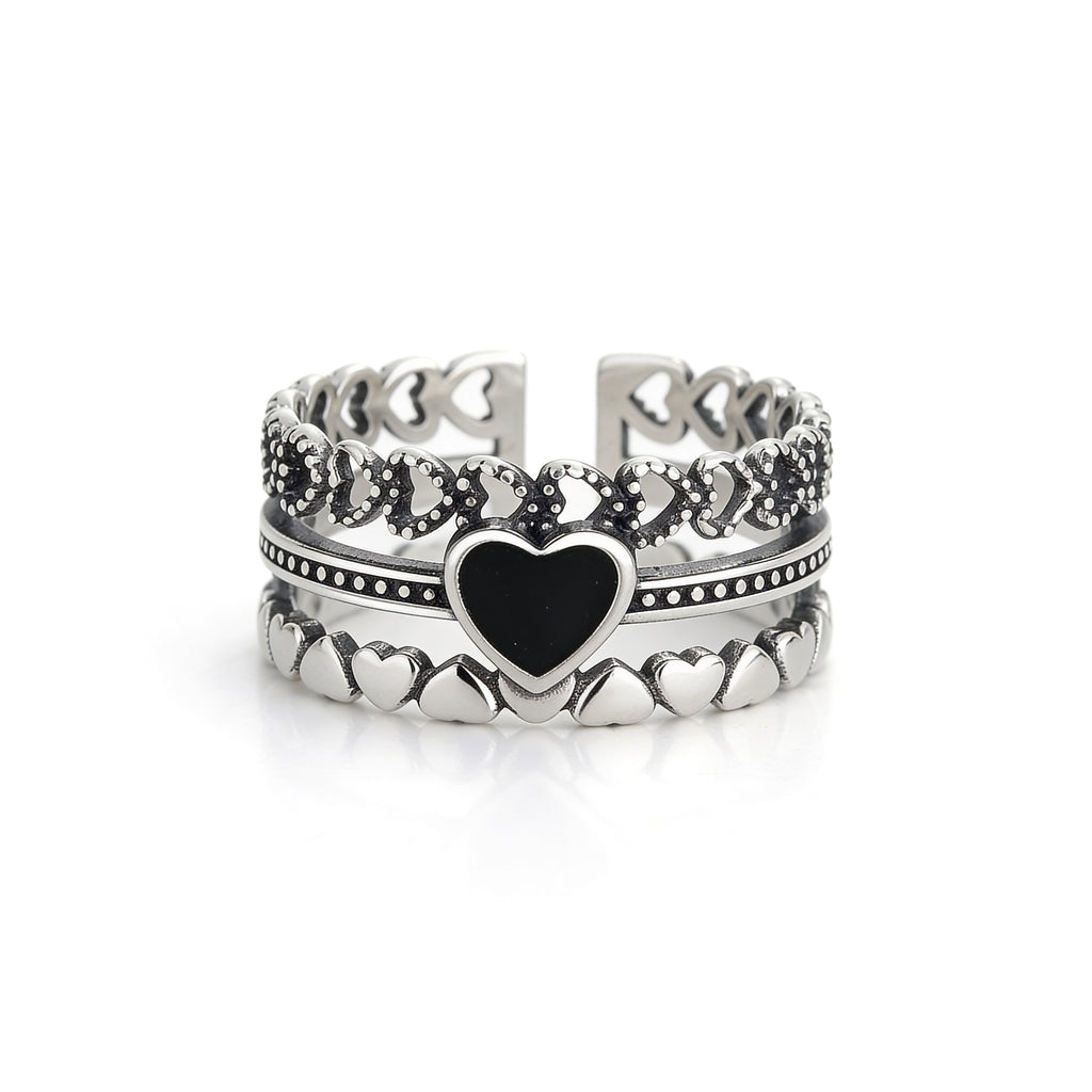 Black heart silver ring worn on hand with stacked layered design and textured detailing