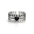 Black heart silver ring worn on hand with stacked layered design and textured detailing
