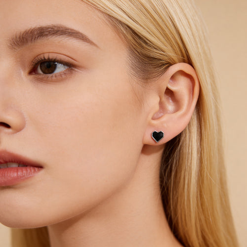 Close up of black heart stud earrings with silver frame.
