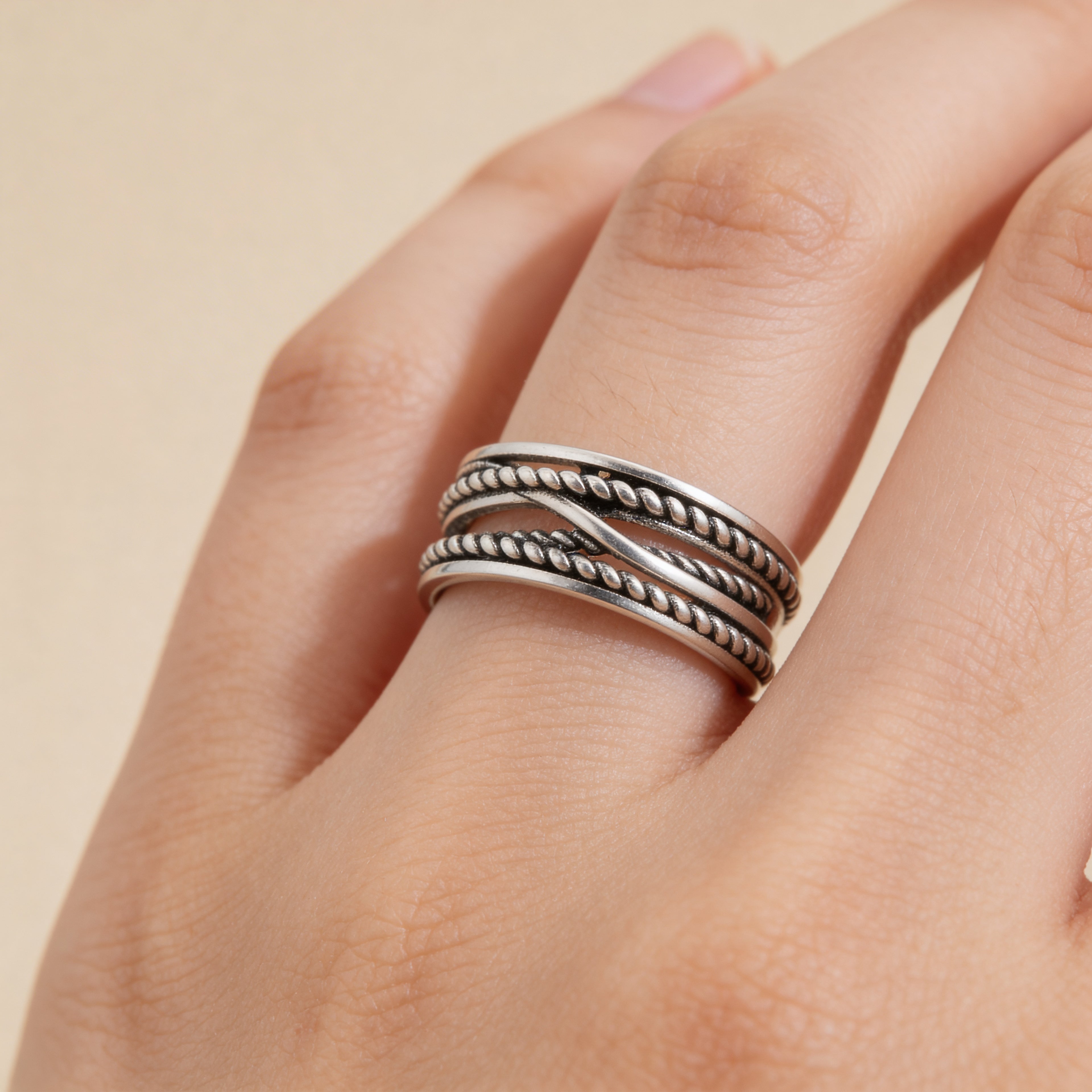 Adjustable silver rope ring worn on finger, textured stacking band for women.