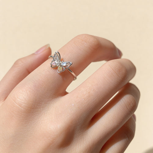 Adjustable silver butterfly ring worn on finger with colorful crystal details.