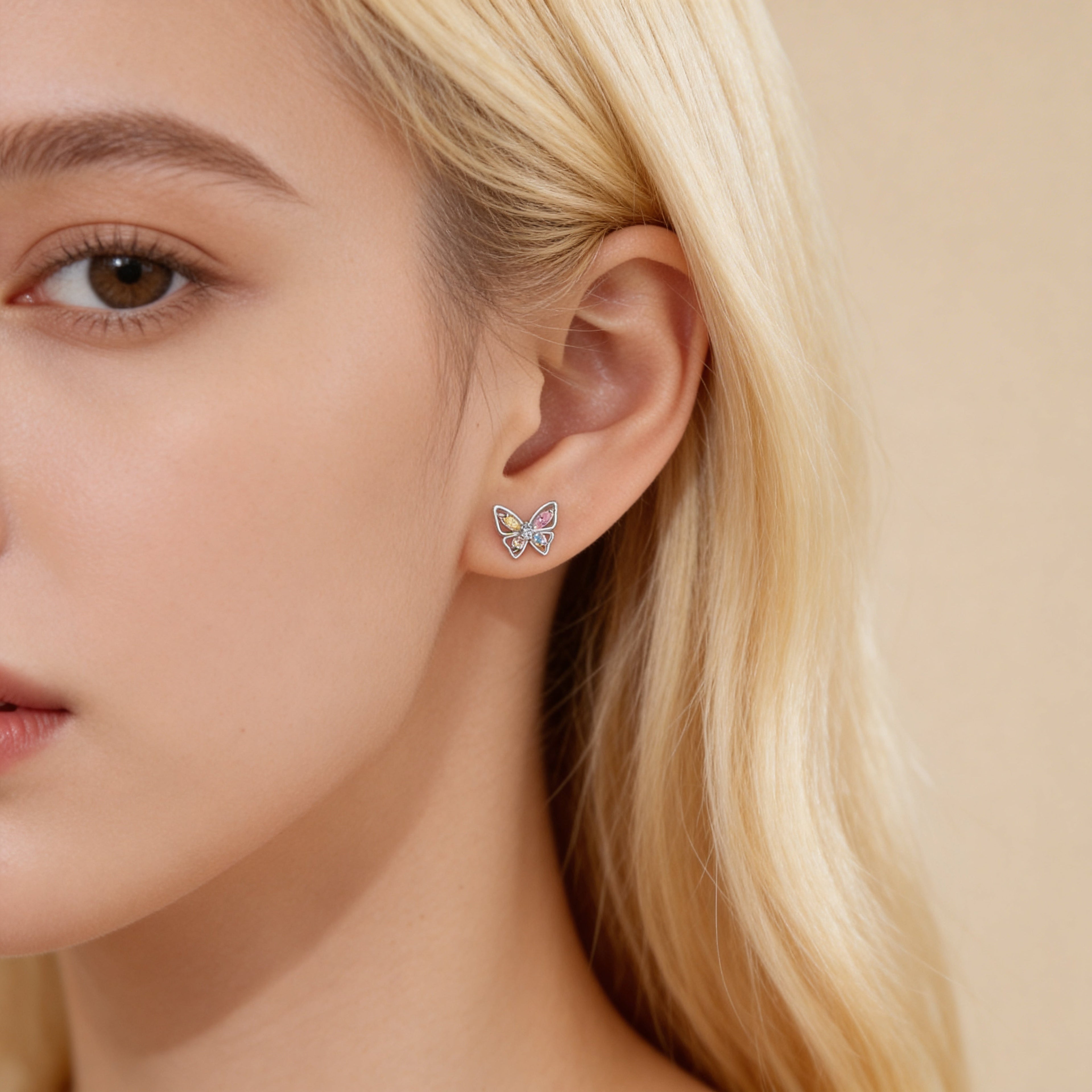 Colourful crystal butterfly stud earrings worn on ear.