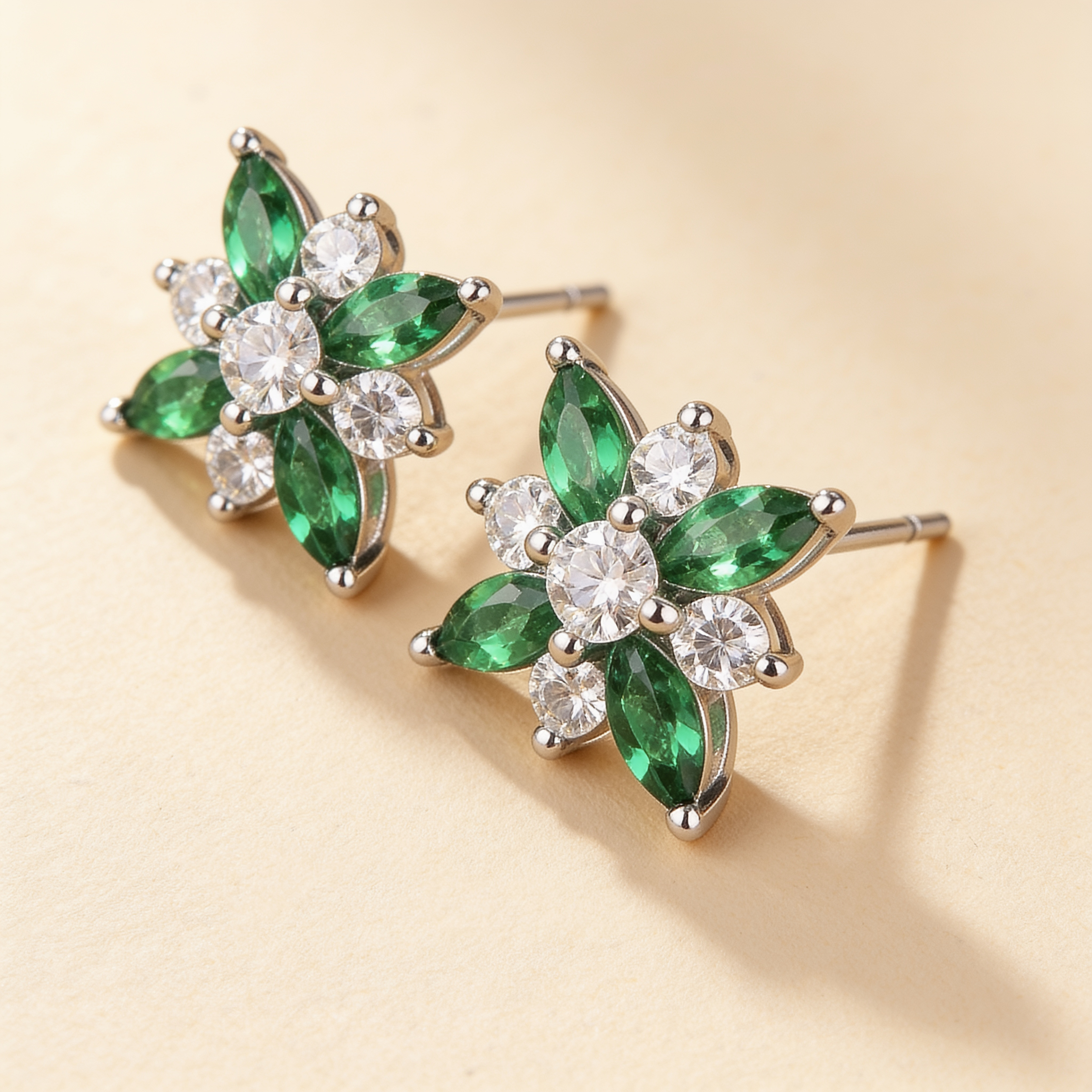 Close-up of silver plated flower stud earrings with green crystal petals and sparkling white cubic zirconia stones