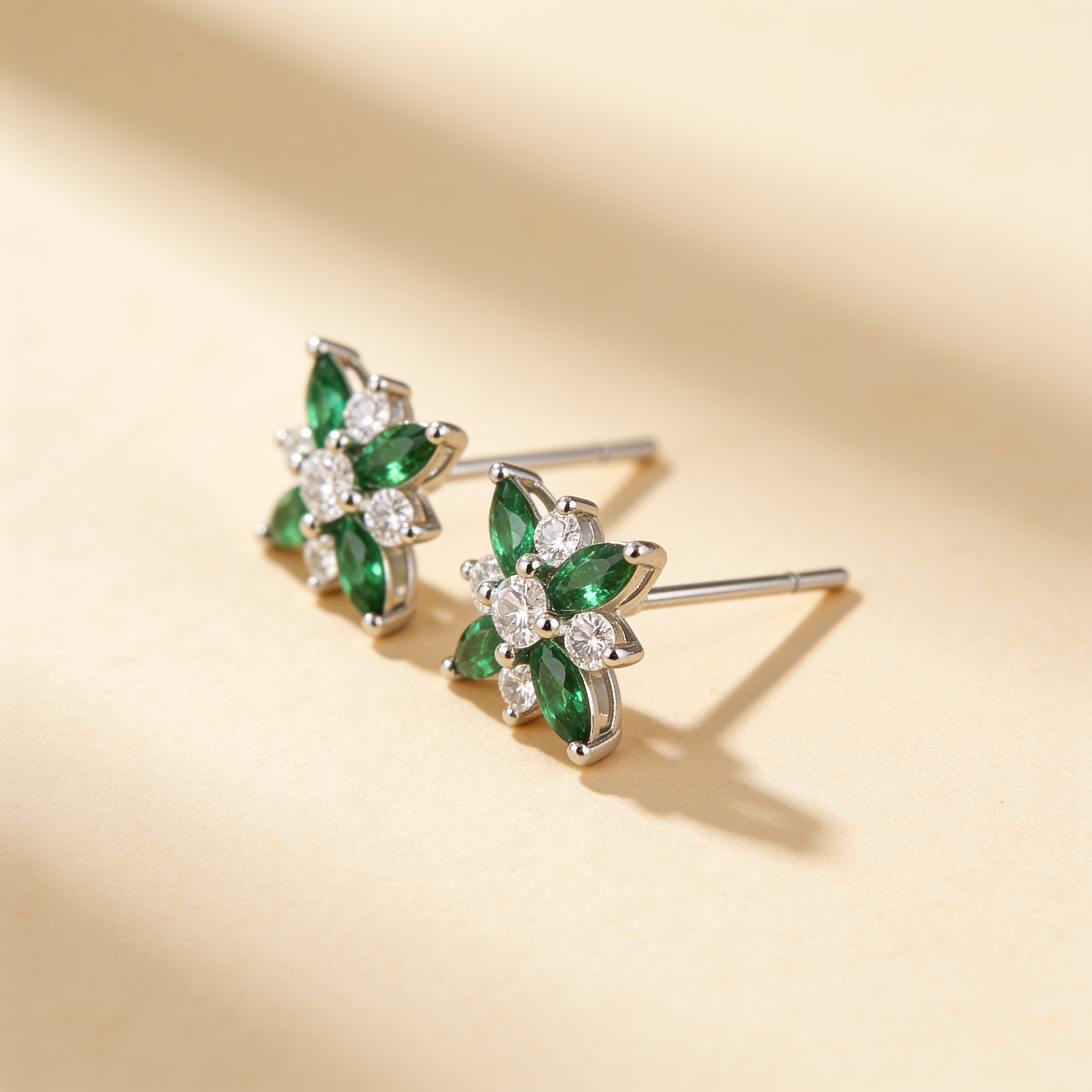Side view of silver plated flower stud earrings with green crystal petals and sparkling white cubic zirconia stones