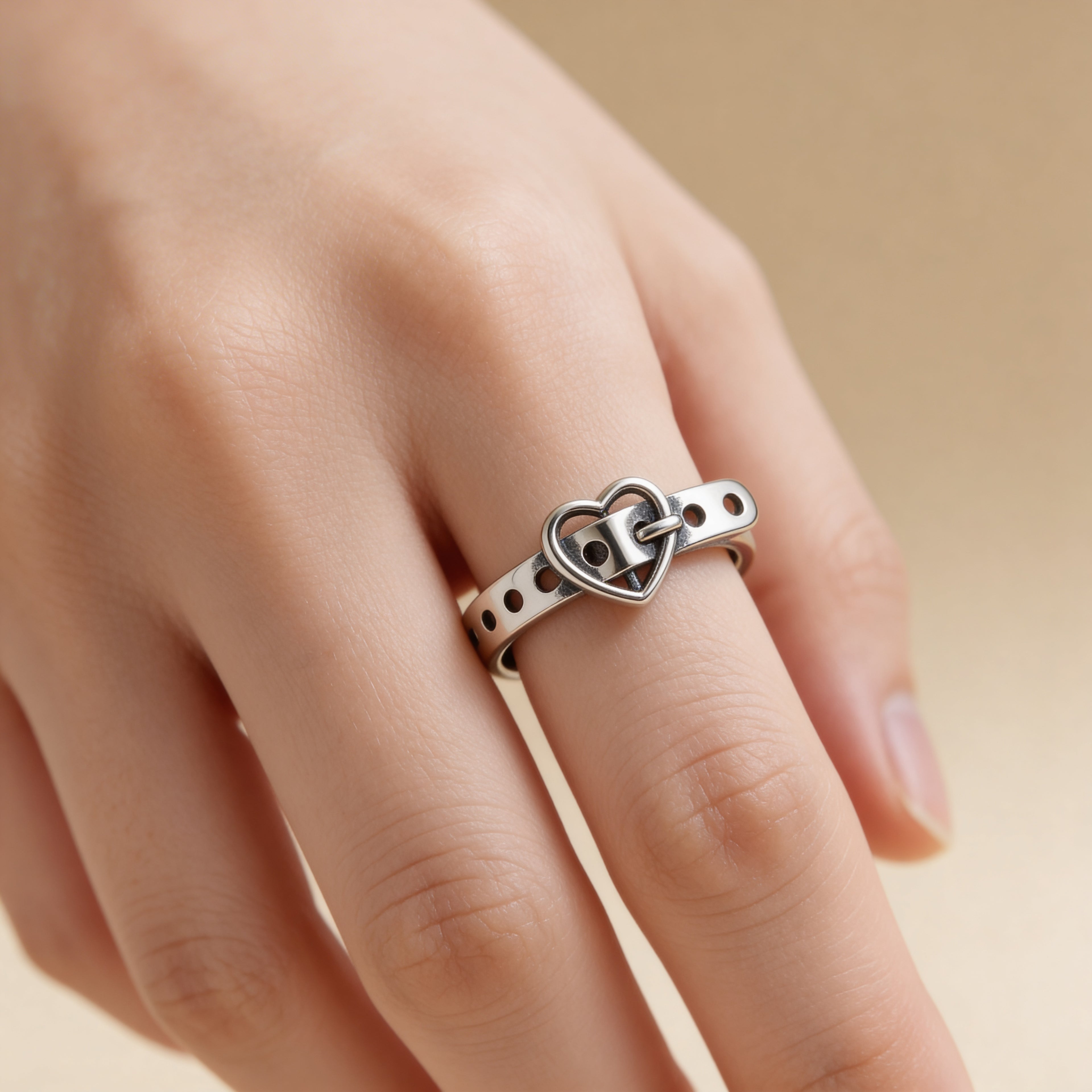 Adjustable silver heart buckle ring worn on finger, modern romantic stacking ring.