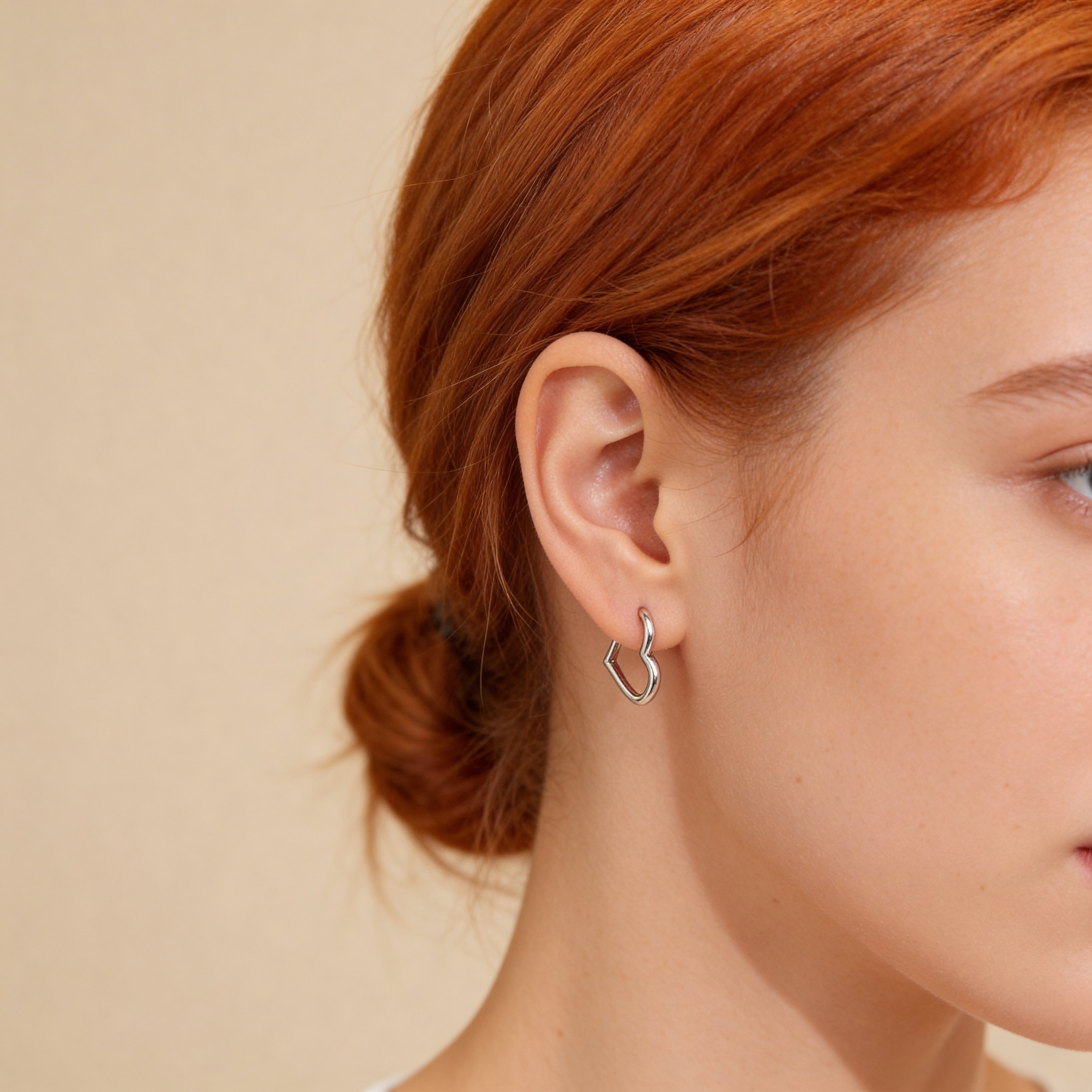 Close up of sterling silver plated heart shaped hoop earrings.