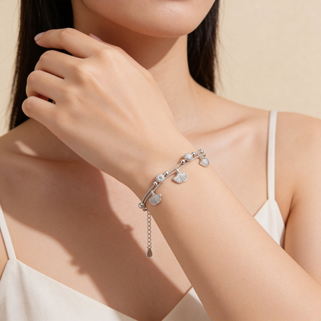 Close up of silver leaf charm bracelet with delicate charms.