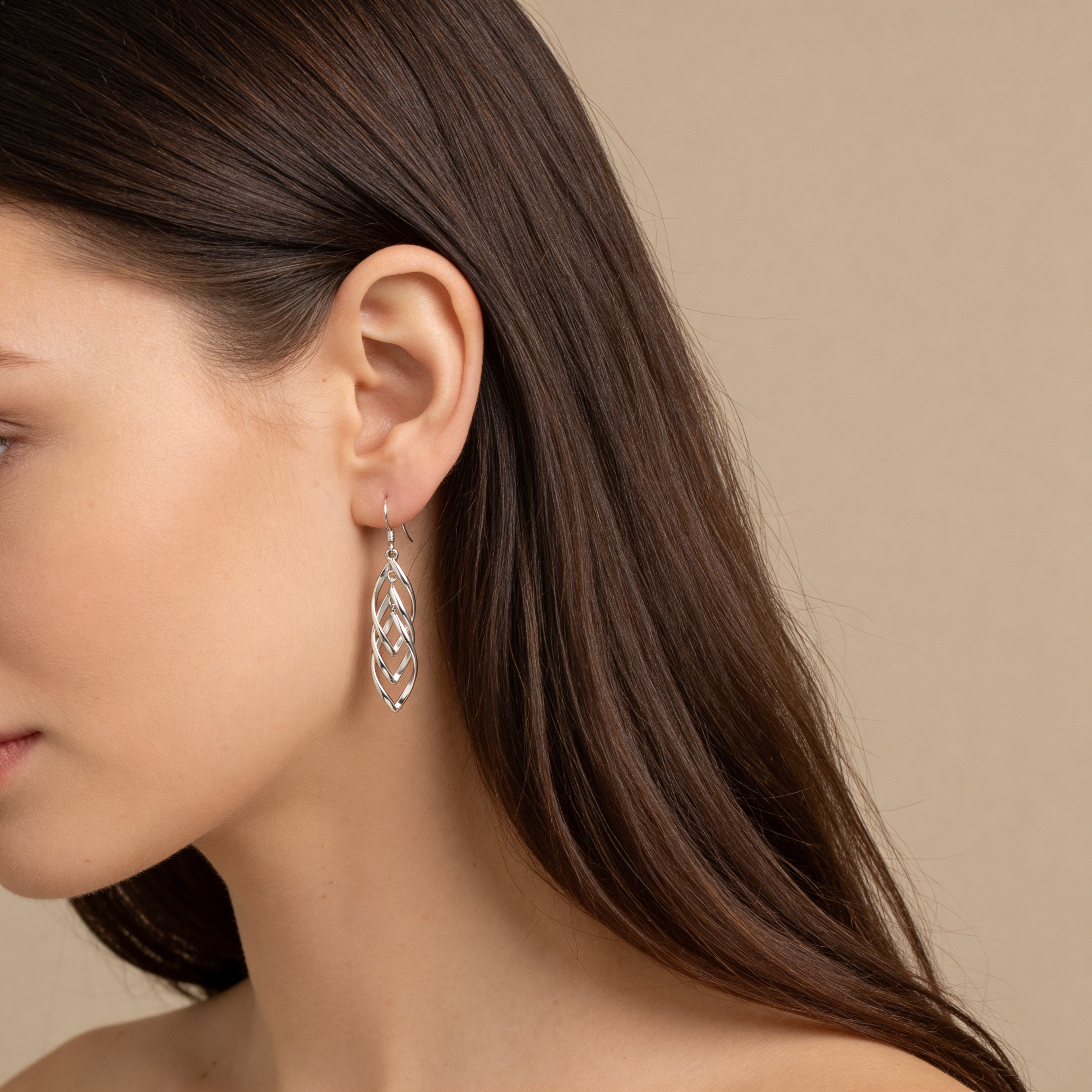Long silver cascading leaf earrings worn on ear.