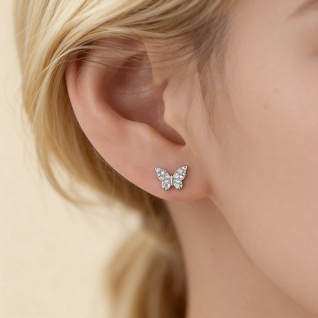 Mini silver plated crystal butterfly stud earring worn on the ear showing its delicate 7mm size