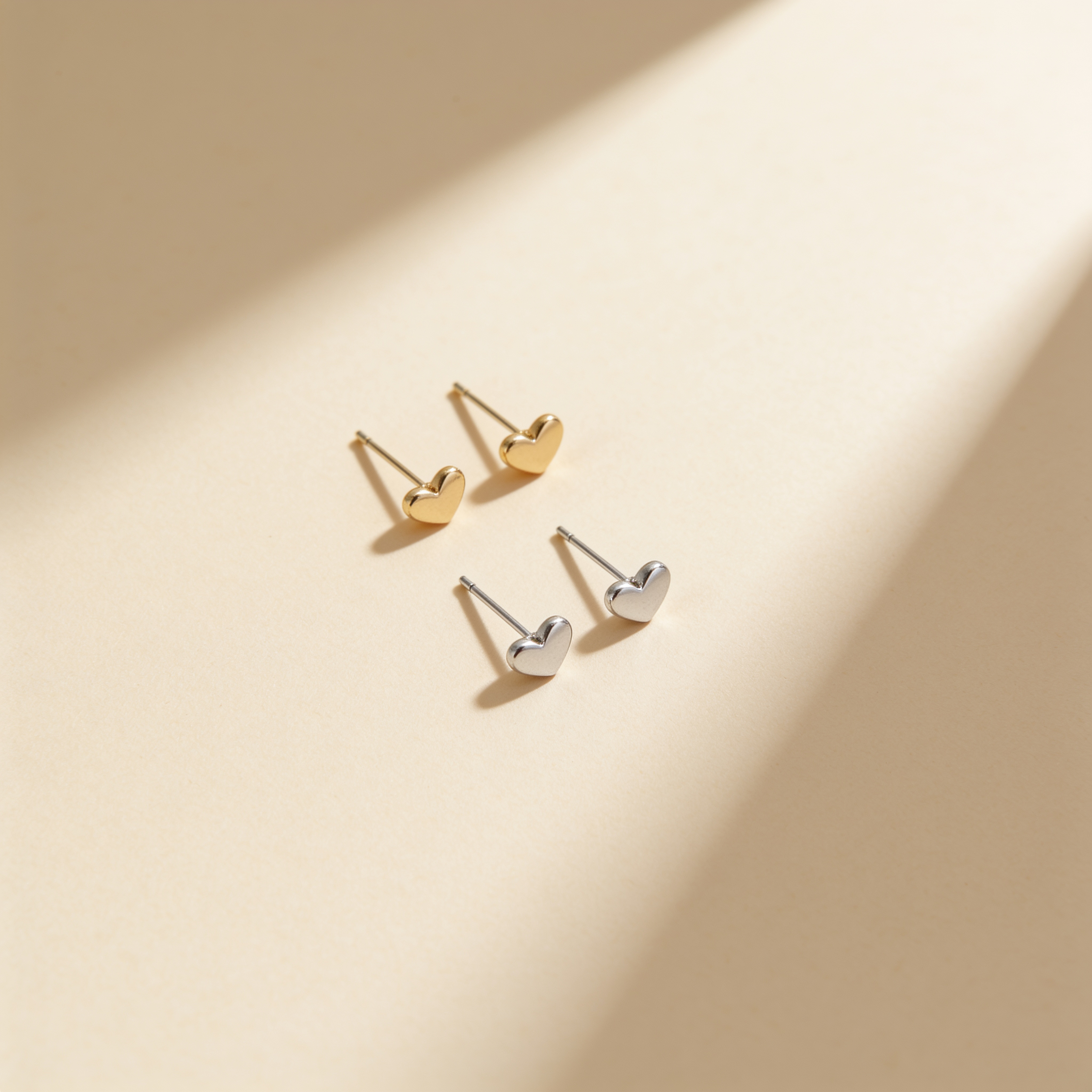 Mini heart stud earrings in gold and silver plated finishes, featuring a polished 4.8 mm heart design