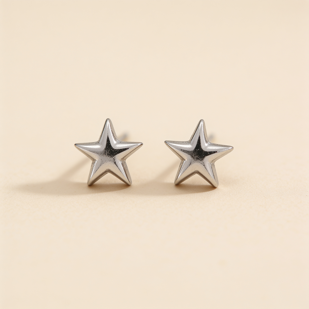 Pair of mini silver plated star stud earrings displayed on a soft beige background