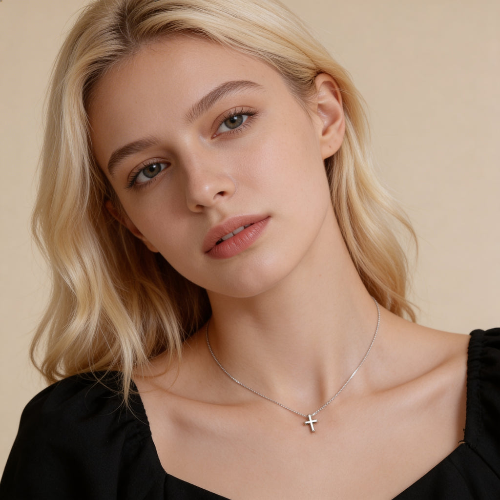 Minimalist silver cross necklace worn by model.