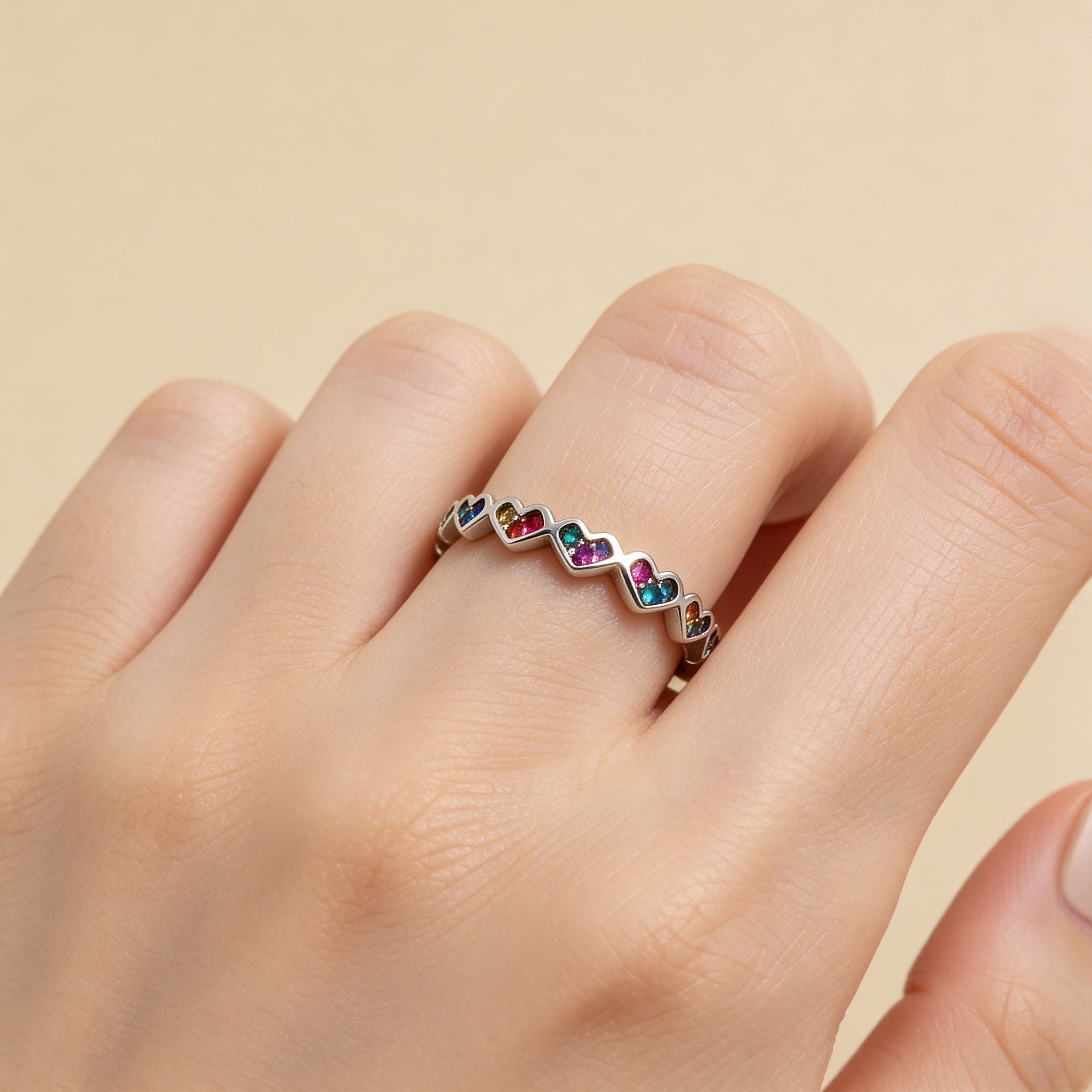 Adjustable silver rainbow heart ring worn on hand, colorful diamante stacking ring for women.