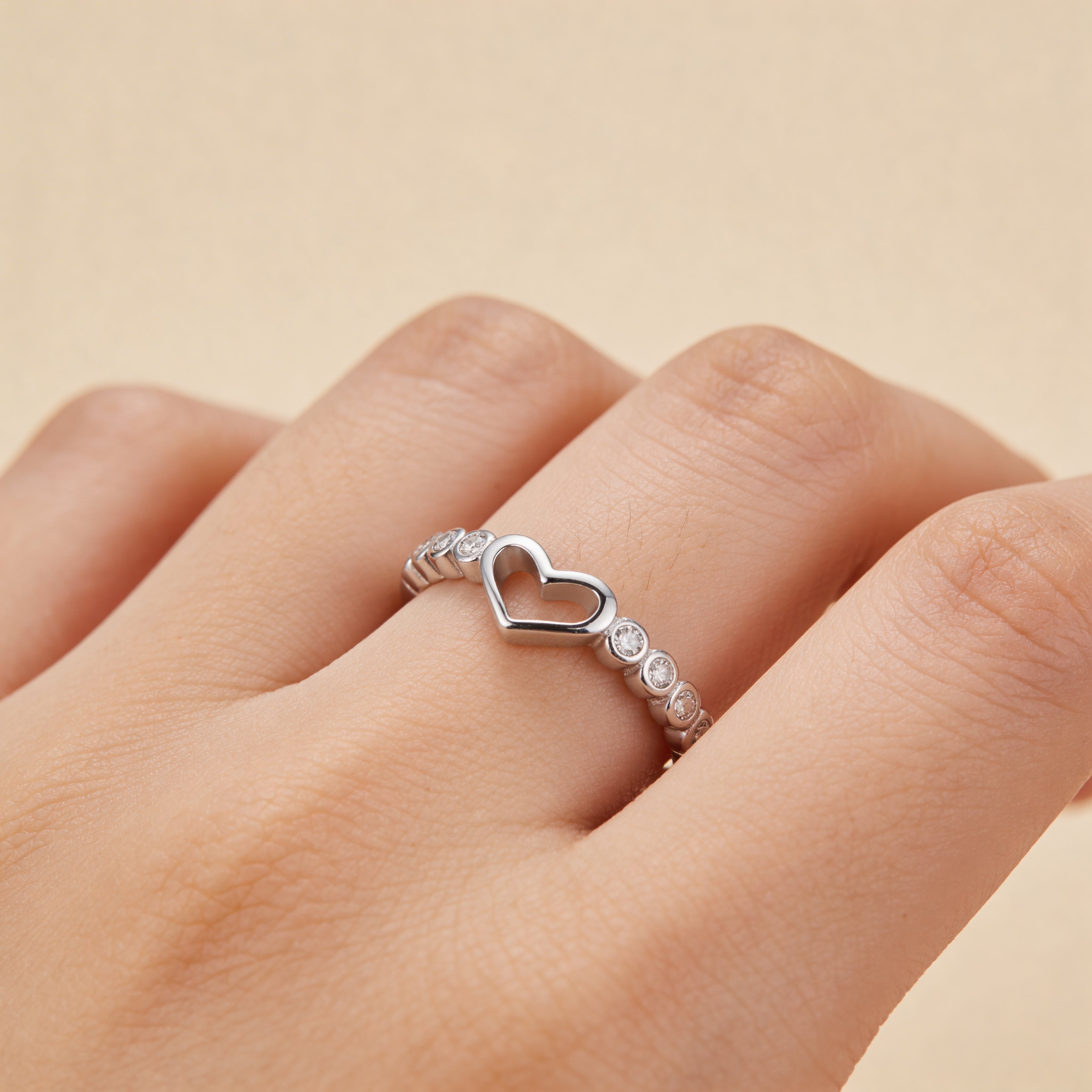 Adjustable silver open heart promise ring worn on hand, dainty stacking jewelry.