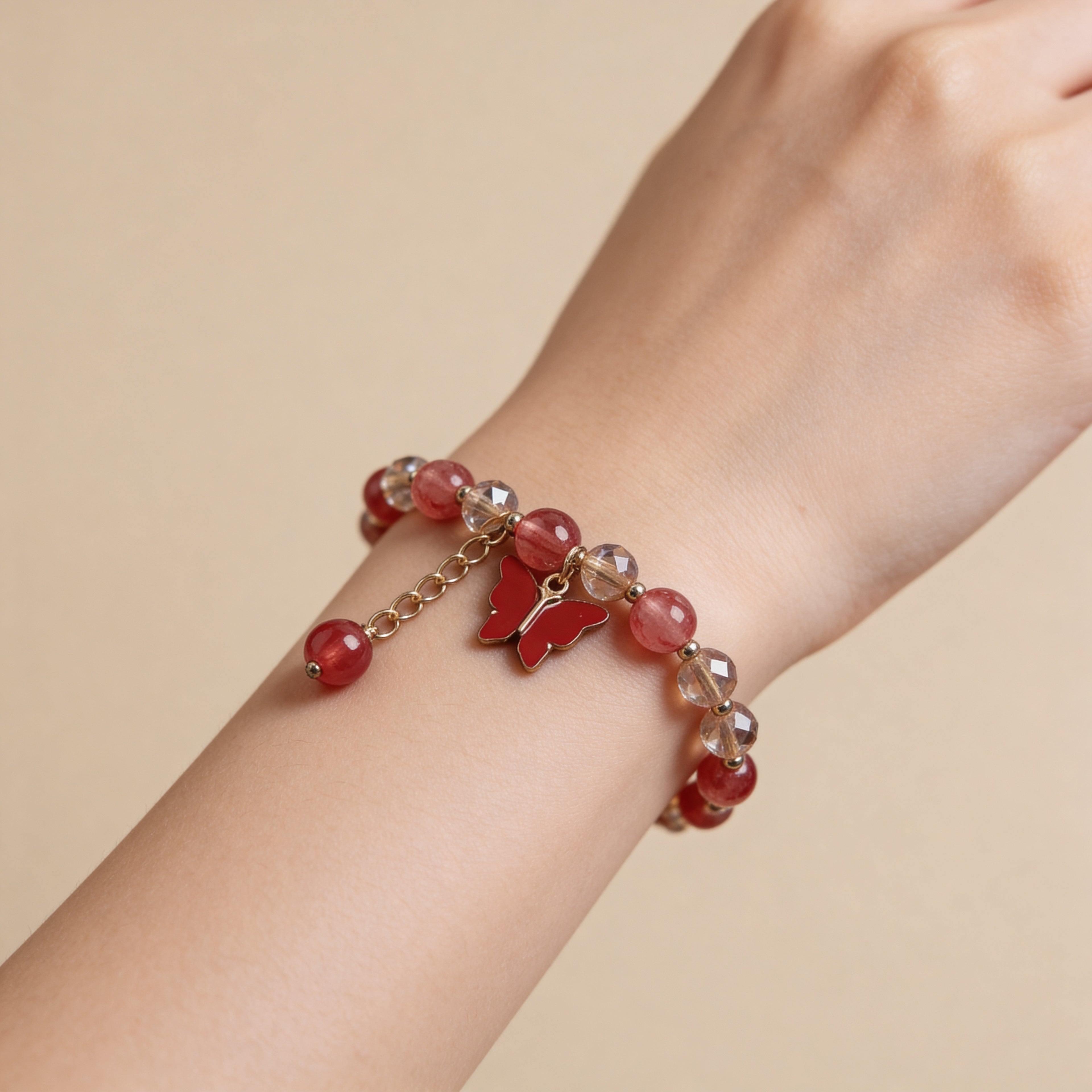 red beaded bracelet with a butterfly charm on a white background