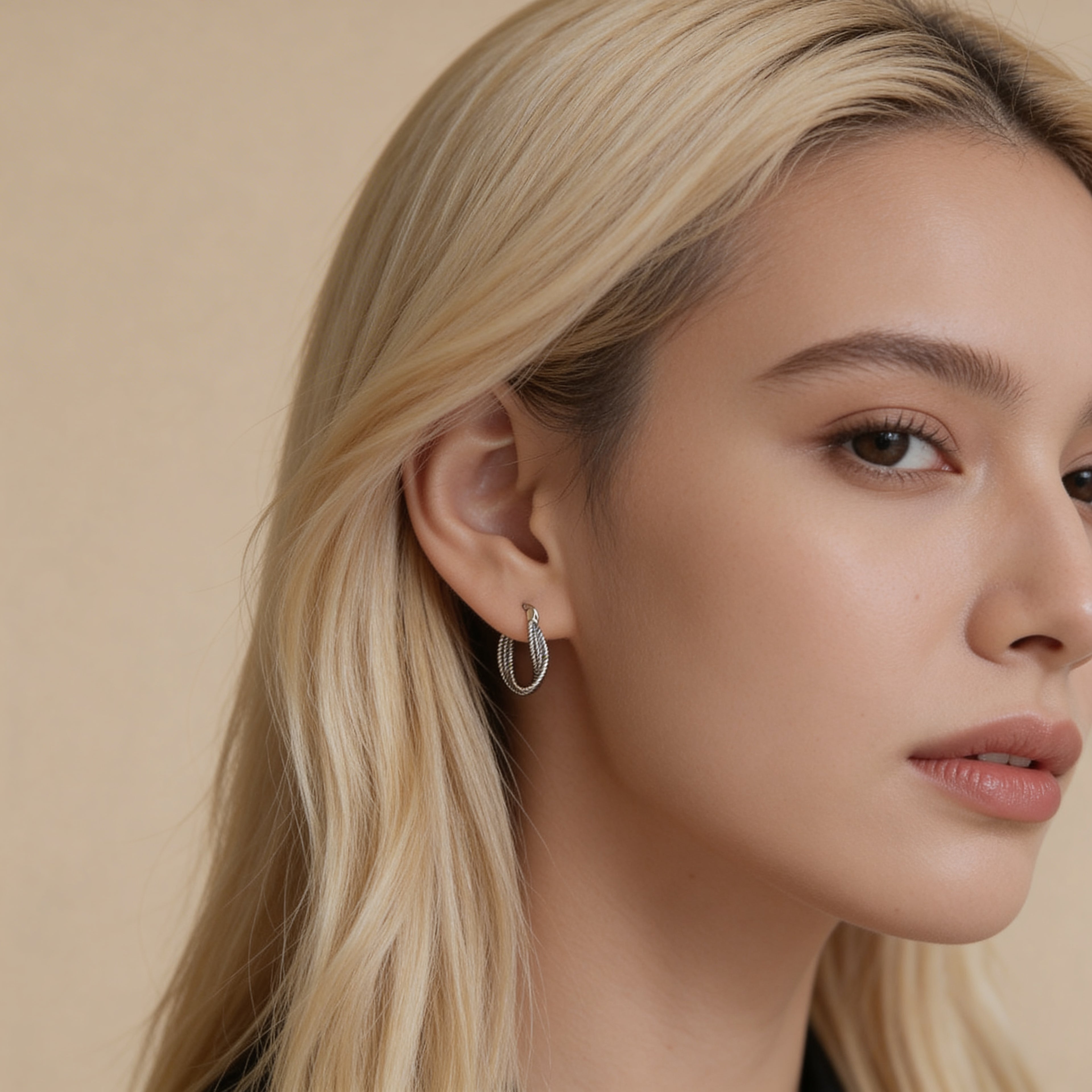 Small silver rope twist hoop earrings worn on ear.