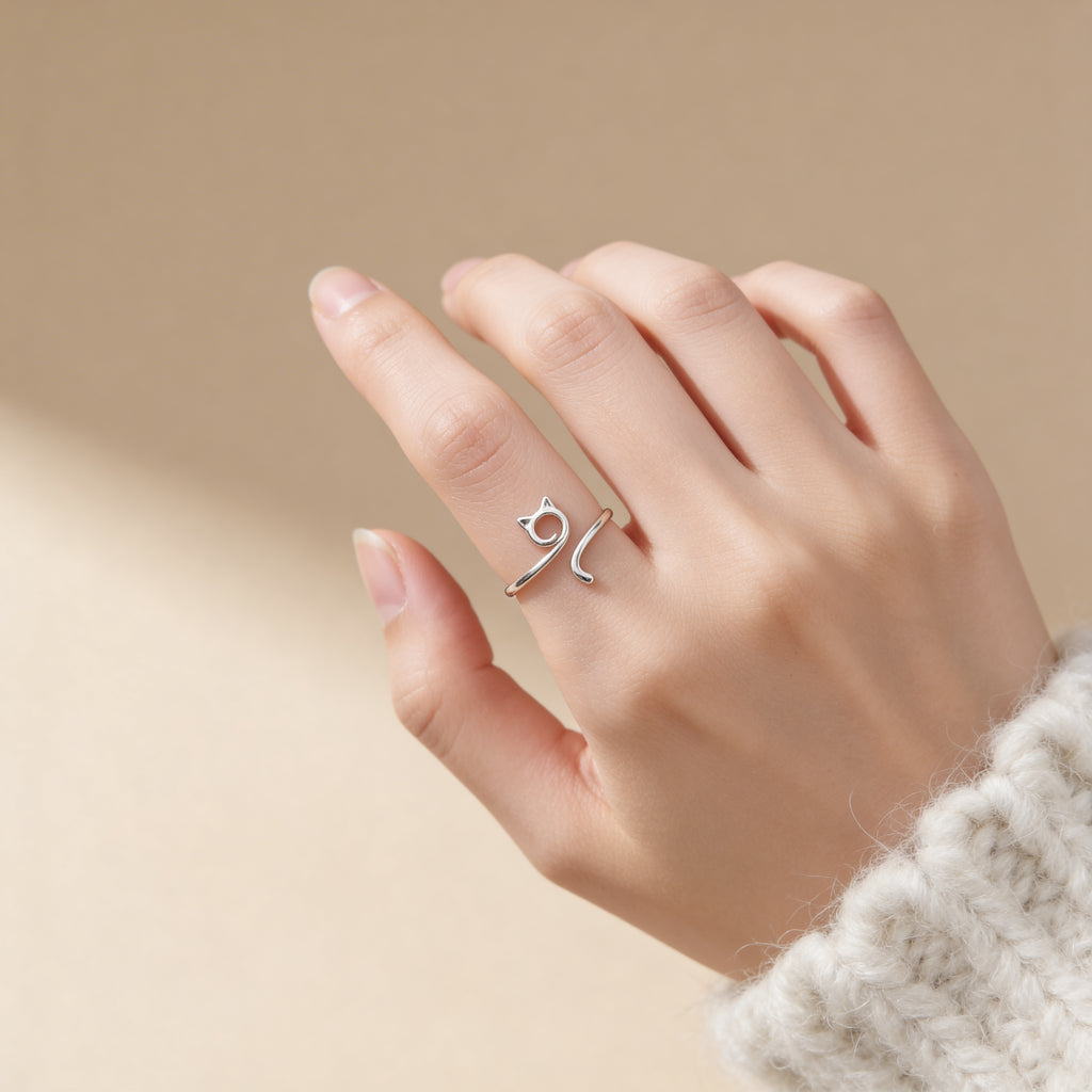 Adjustable silver cat ring worn on finger, cute minimalist animal jewelry.