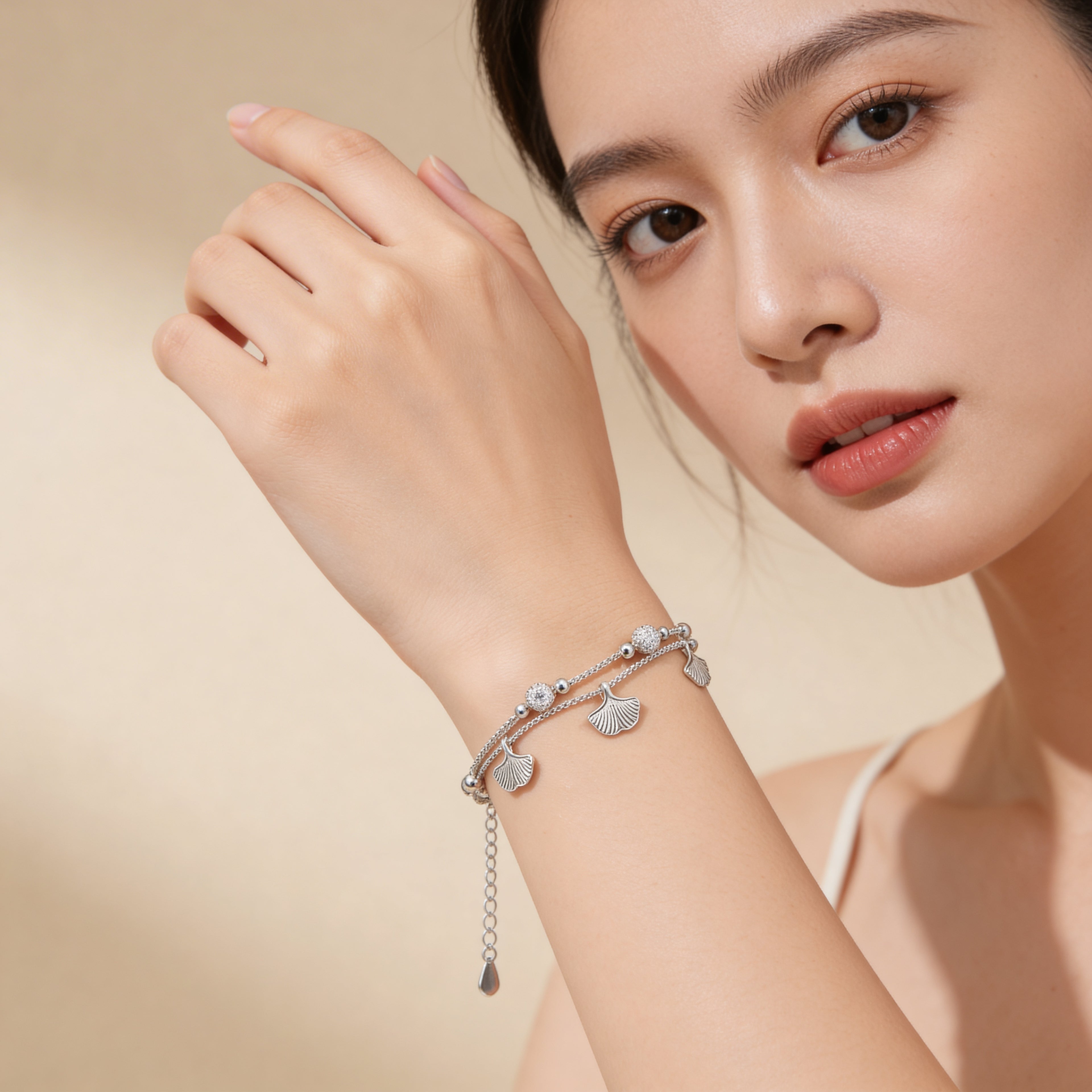 Silver plated leaf charm bracelet worn on wrist.