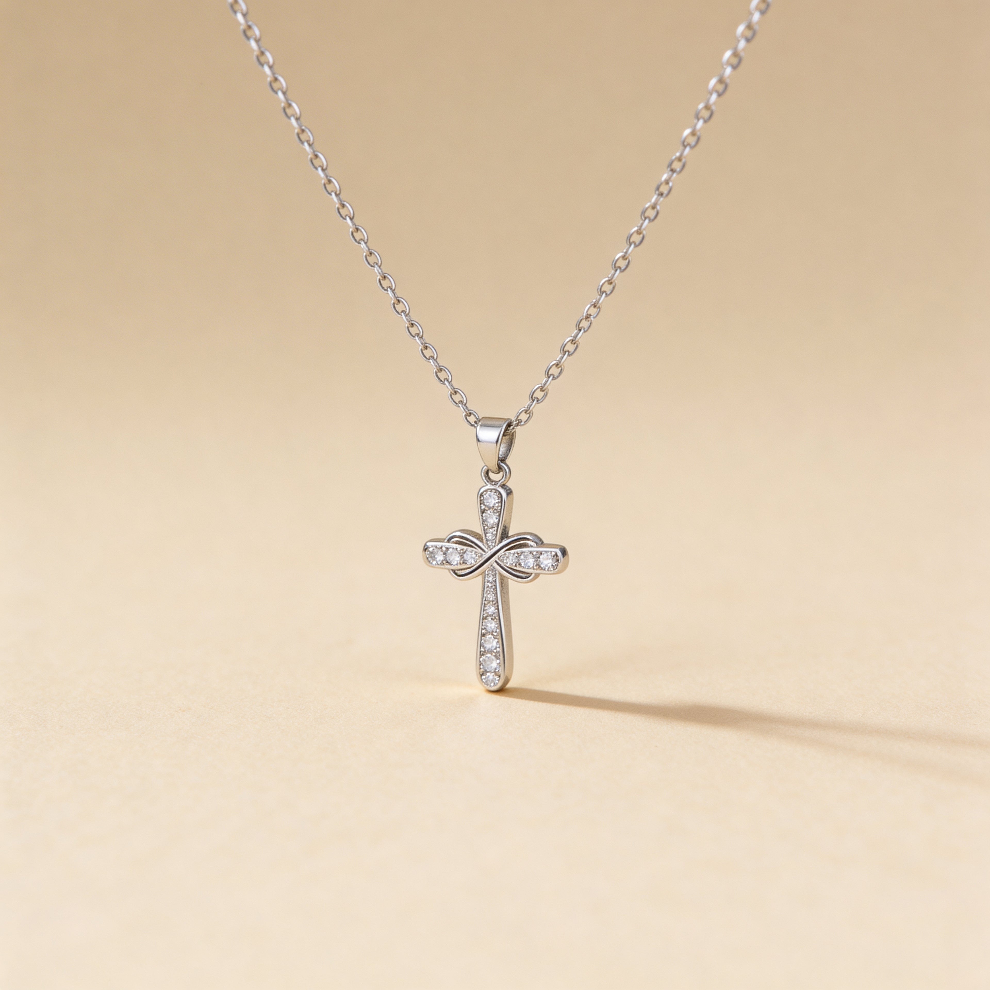 Silver cross pendant necklace on a beige background