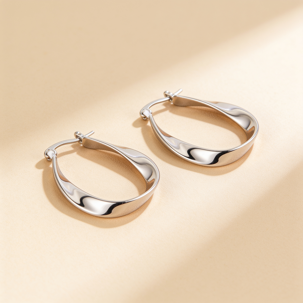 Pair of silver plated twisted hoop earrings with a polished wavy design displayed on a warm beige background